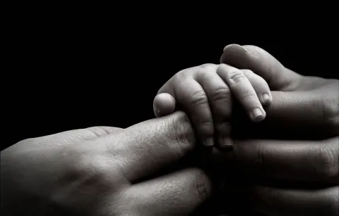 Babyhand in Hand eines Erwachsenen
