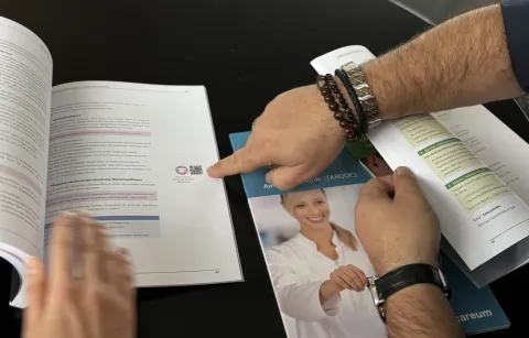 Drei Bücher des Careum Verlags liegen aufgeschlagen auf dem Tisch. In einem ist ein QR-Code zu sehen.