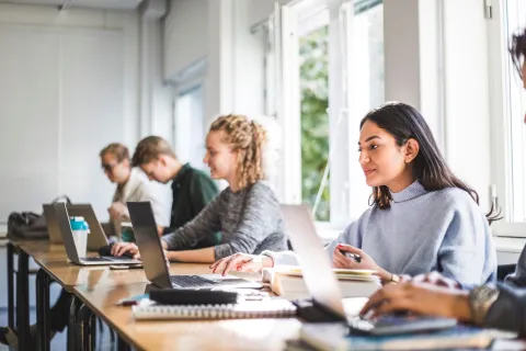 Mehrere Studenten sitzen vor Laptops in Klassenzimmer