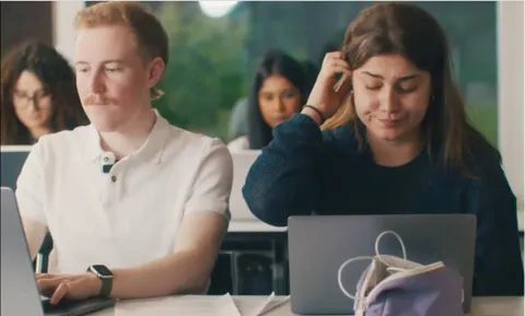 Lernende sitzen in einem Klassenzimmer vor ihrem Laptop