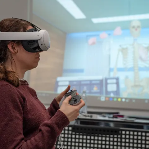 Frau mit VR-Brille betrachtet anatomisches Skelett in der Gesundheitsausbildung